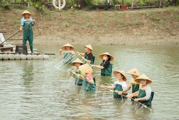 著青蛙裝坐膠筏下魚池圍網捕魚