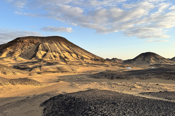 黑白沙漠
埃及西部的黑白沙漠宛如大地的畫布,以極致對比的色彩展現荒野的神祕。黑沙漠覆蓋著遠古火山噴發後的黑色玄武岩碎片,穿越這片黑色大地步入截然不同的白沙漠,風蝕雕刻出的白色石灰岩奇岩林立,光影在黑與白之間交錯,如幻境般綻放在金色沙丘之間