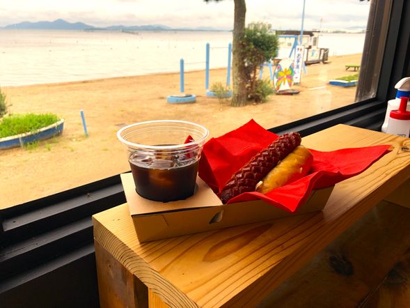 ビーチで朝食タイム
SUP体験後は、真野浜の砂浜にて、地元の宿・きよみ荘特製のご当地ホットドッグ「近江だっける」をご用意。びわ湖を眺めながらのんびりとした朝のひとときをお楽しみください。