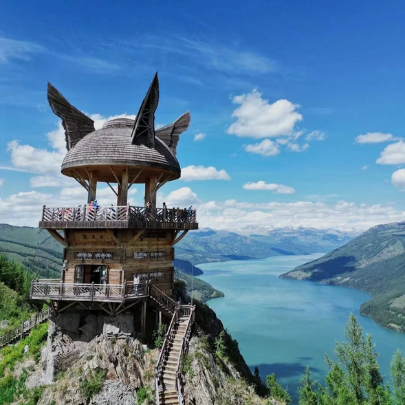 今天我們將前往北疆最令人嚮往的秘境【喀納斯】,深入探索其三大經典景點:臥龍灣、月亮灣和神仙灣。每一處都宛如仙境,展現出自然的極致之美。
最後抵達【賈登峪】,在寧靜的環境中為接下來的旅程養精蓄銳。
【觀魚台】是喀納斯景區的標誌性景點之一,
位於喀納斯湖的高處,是俯瞰整個湖區全景的最佳位置。
台子建在海拔2000多米的山巔,沿著木質階梯攀登而上,途經原始森林和茂密的植被,旅途中不時可以看到可愛的松鼠和各種鳥類,讓人感受到大自然的生機與活力。
站在觀魚台上,整個喀納斯湖如一塊碧綠的翡翠鑲嵌在山谷間,四周是連綿的雪山和原始森林,景色壯麗無比。湖水的顏色隨著天氣和光線的變化而變幻,從湛藍到翠綠,宛如魔法般神奇。據說,觀魚台也是傳說中巨型鯤魚現身的最佳觀察點,增添了幾分神秘色彩。