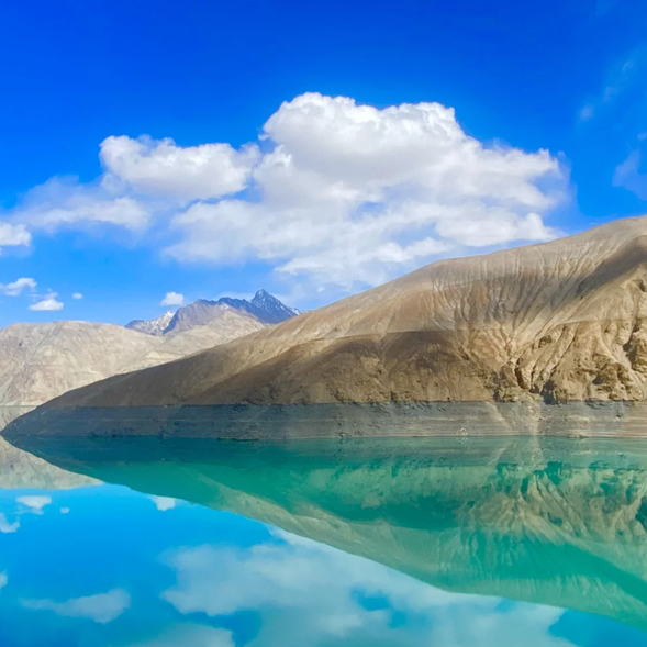 【班迪爾藍湖】位於帕米爾高原深處,是一片隱藏於群山之中的瑰麗湖泊,以其純淨湛藍的湖水而得名。湖面如同一塊藍寶石,倒映著雪山與藍天,四周環繞著寧靜的高原草甸,宛如仙境。