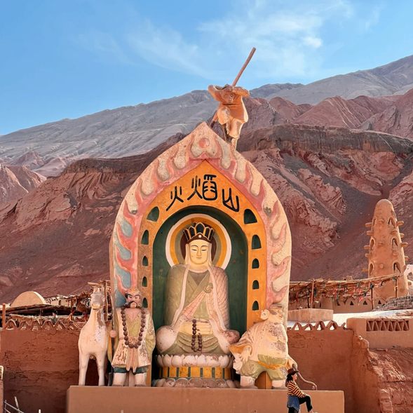【火焰山】位於吐魯番盆地,是《西遊記》中孫悟空大鬧的經典場景,也是吐魯番地區的地標性景點。火焰山以其鮮紅的山體和如火焰般的外觀而得名,山勢連綿起伏,猶如一條巨龍盤踞在大地之上。夏季時,地表溫度可達70℃以上,堪稱“中國最熱之地”。遊客可以在景區內近距離觀賞這片奇異的自然景觀,並了解這片土地背後的地質與文化故事。
