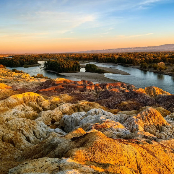 【五彩灘】
位於布爾津河的北岸,是一處因風蝕和水蝕作用形成的典型丹霞地貌,被稱為“櫻桃石灘”。這裡的山體由多種礦物組成,在陽光的照射下展現出紅、橙、黃、綠、紫等鮮豔色彩,如一幅色彩斑斕的油畫。五彩灘的獨特之處在於它與河對岸的綠色植被形成鮮明對比,一邊是荒涼的彩色山丘,另一邊是郁郁蔥蔥的綠洲,視覺效果極具衝擊力。傍晚時分,河面倒映著山丘和落日的餘暉,更是美得令人屏息。作為攝影愛好者的天堂,五彩灘的每一處角落都能讓人捕捉到大自然的鬼斧神工。