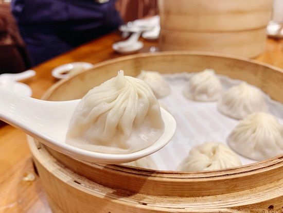 鼎泰豐(ディンタイフォン)ランチ(新生店)
ランチは名高い鼎泰豐 新生店 で。ガラス越しに、職人が小籠包を手作りで包む手際の良い姿を見ることができます。一つ一つの小籠包は皮が薄く透明で、蒸した後は香りと旨味が広がります。口に入れるとスープが口の中で溢れ、鼎泰豐がミシュランガイドに掲載され、世界的な名店として評価される理由を実感できます。小籠包だけでなく、ヘチマと海老のスープ包み、紅油ワンタン、スペアリブチャーハンなども見逃せない定番メニューです。
