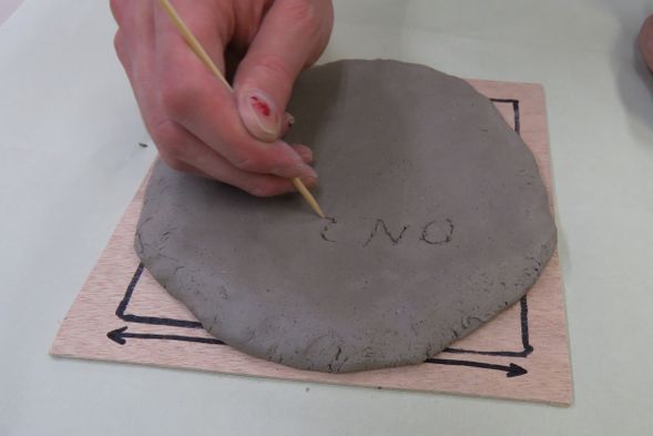6 サインを書く:お皿の裏面に自分の作品と分かるようにサインを入れましょう。竹串を使って書きます。深く入れすぎないように